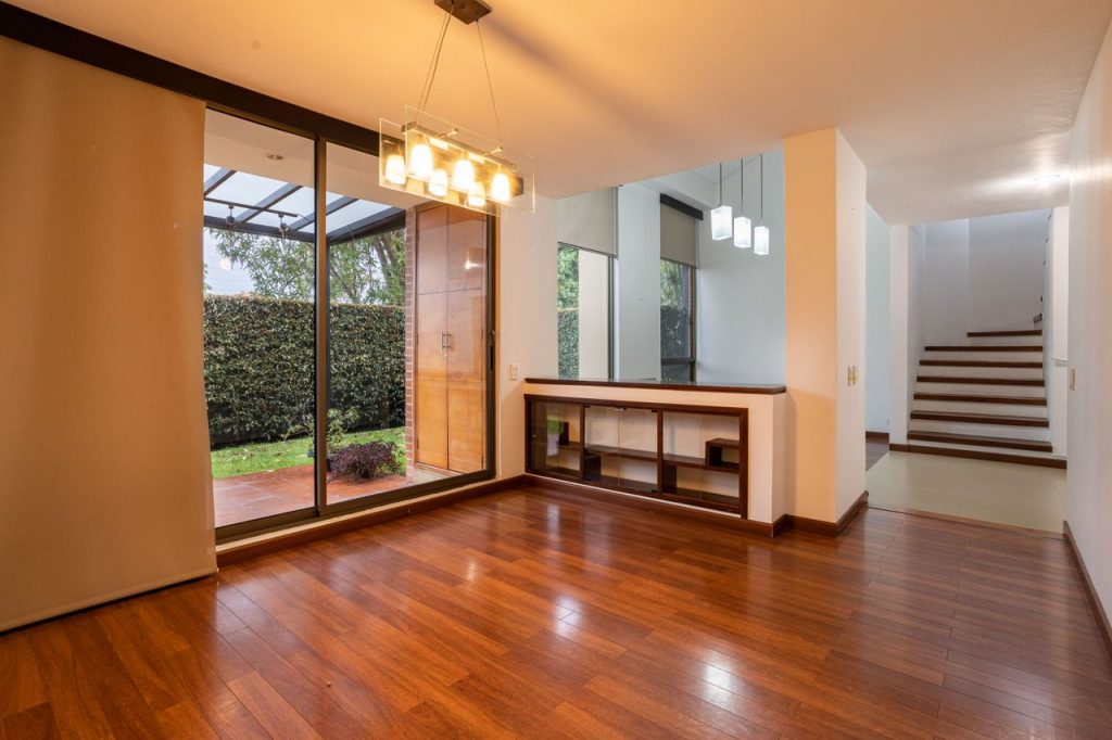 Bright minimalist living space with wooden flooring and glass doors leading outside.