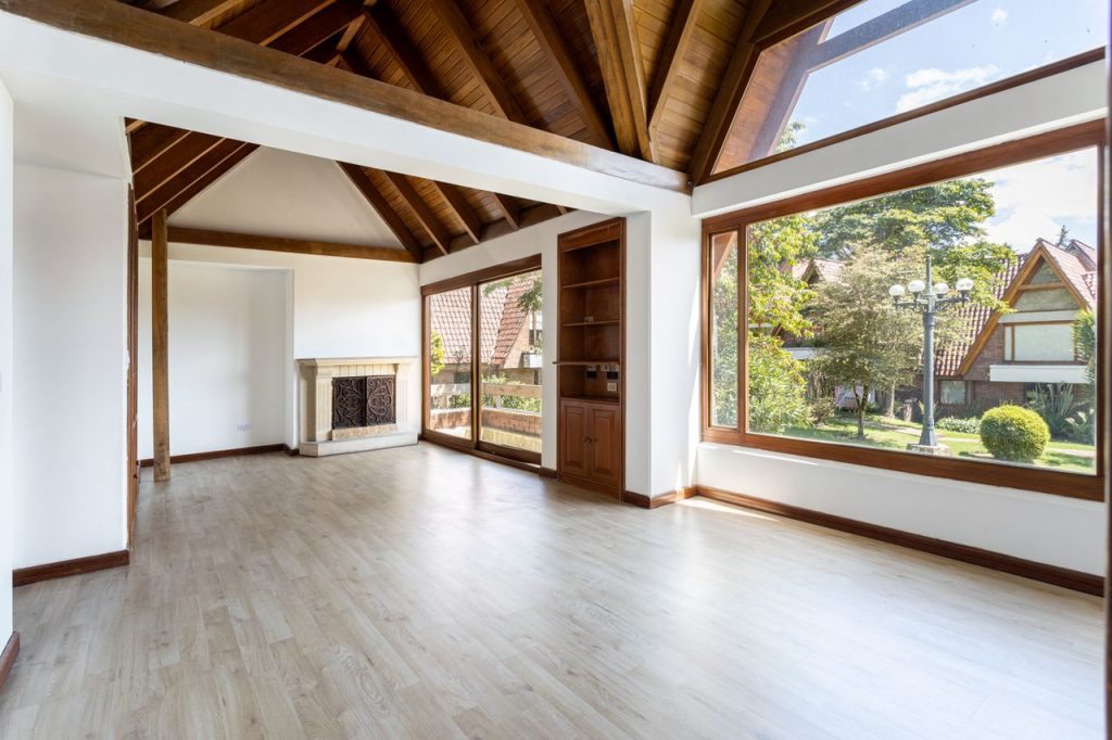 Spacious modern living room with large windows and wooden ceiling, located in Bogotá, Colombia.