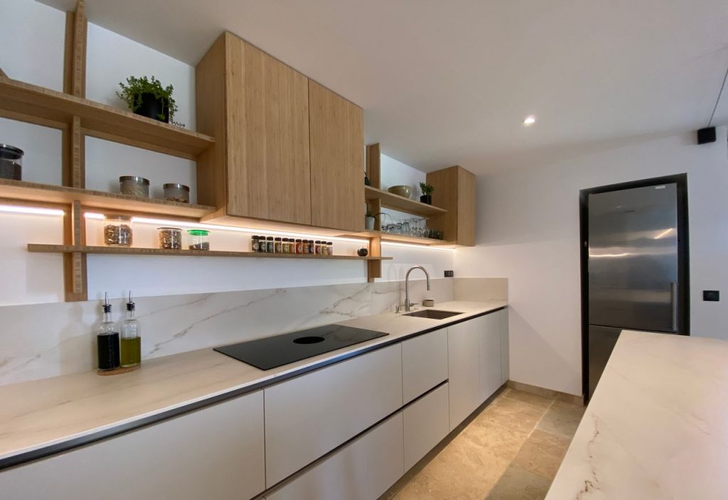 Contemporary kitchen with sleek design, wooden shelves, and marble countertops.