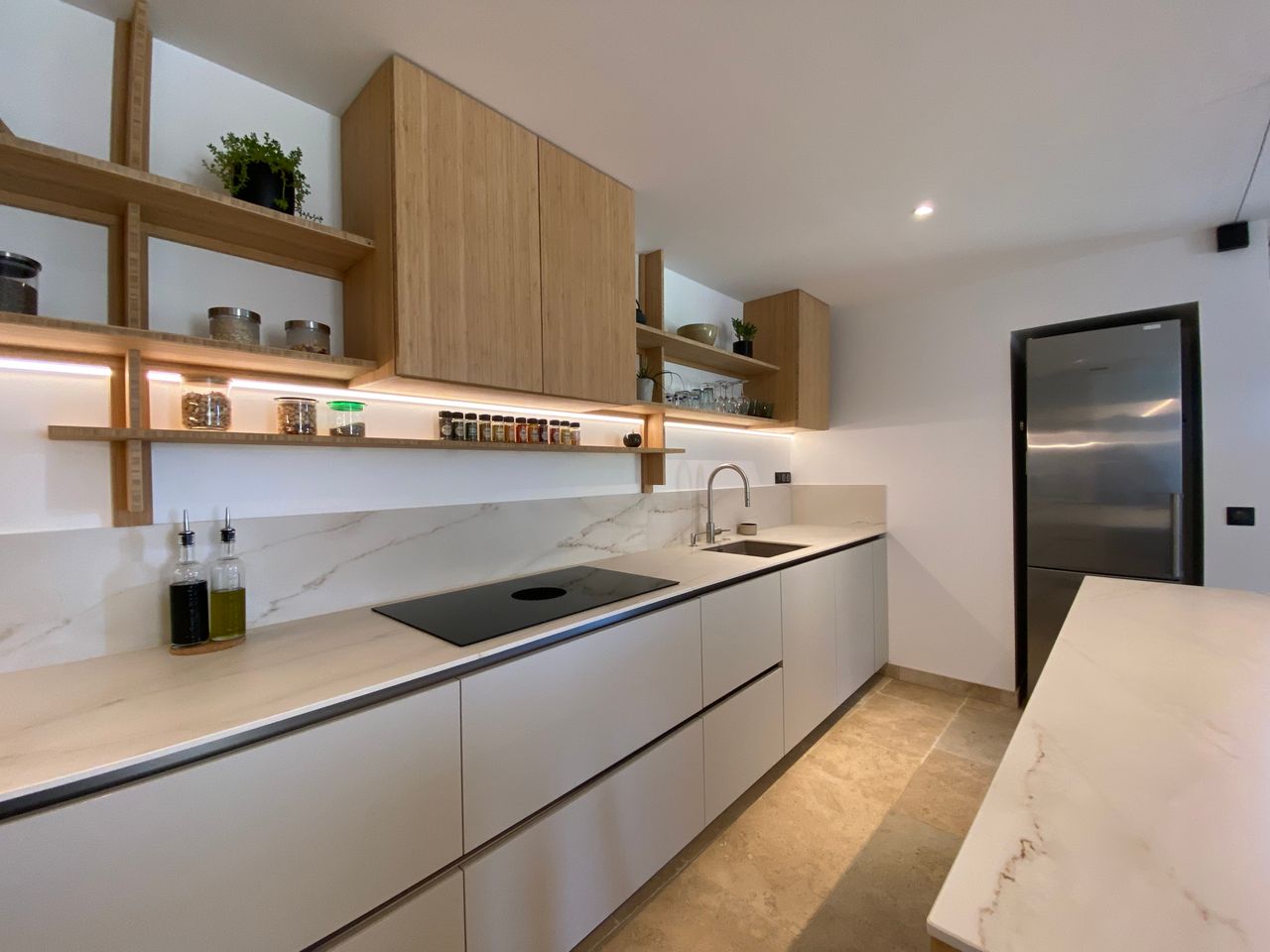 Contemporary kitchen with sleek design, wooden shelves, and marble countertops.