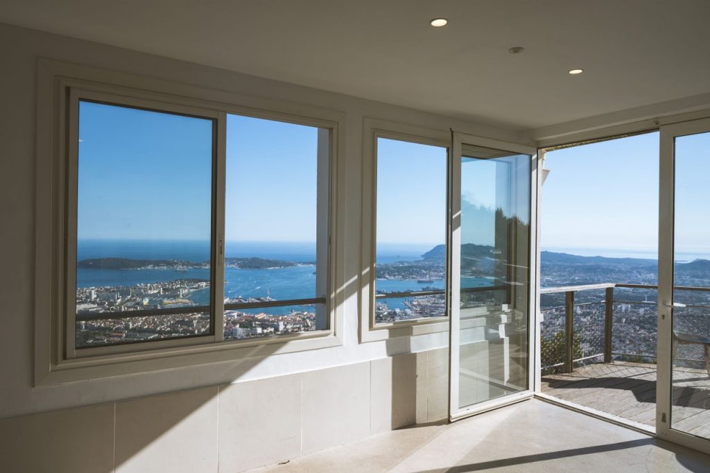 Stunning interior view of Toulon, France with large windows showcasing the coastline and cityscape.
