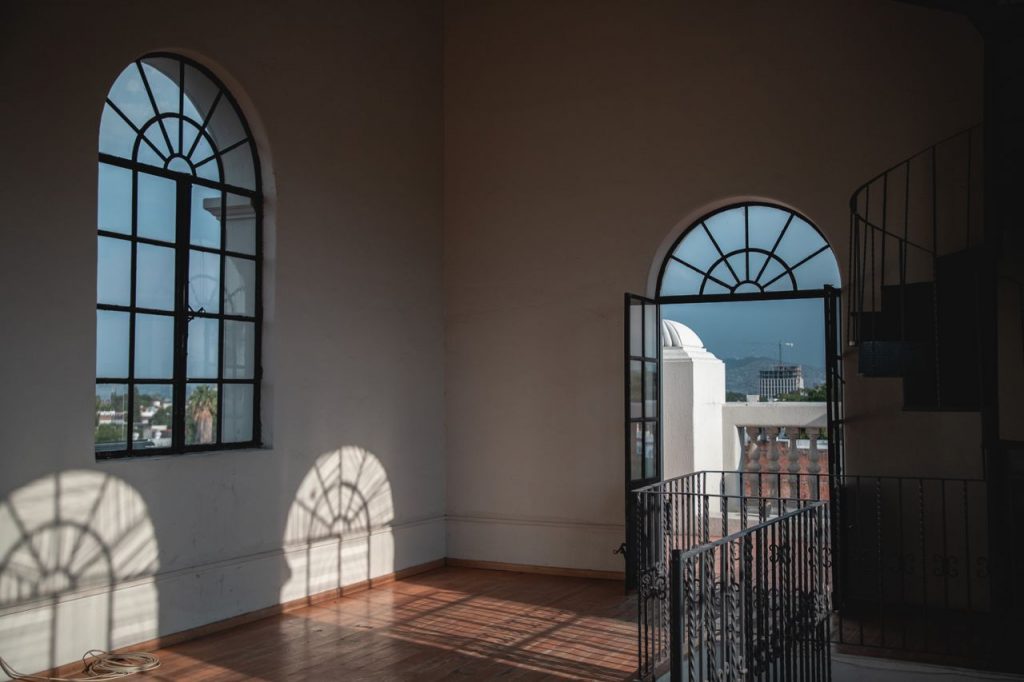 Sunlit interior room with arched windows in Guadalajara, Mexico, casting intricate shadows.