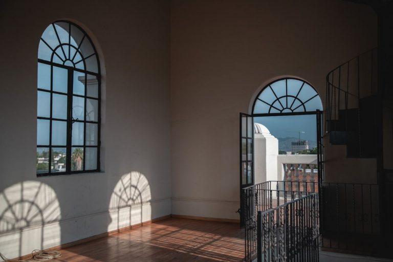 Sunlit interior room with arched windows in Guadalajara, Mexico, casting intricate shadows.
