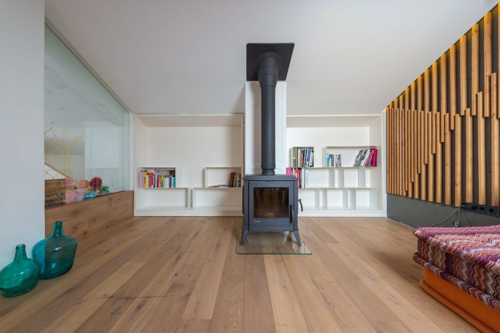 Spacious light living room with fireplace near shelves decorative vases and comfy couch