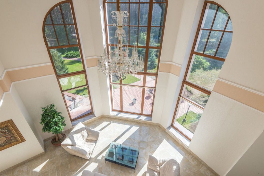 Spacious living area with floor-to-ceiling windows, elegant seating, and a grand chandelier.